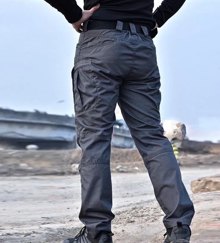 Outdoor multi-legged tactical pants in khaki cotton blend with multiple pockets on legs, shown against natural background