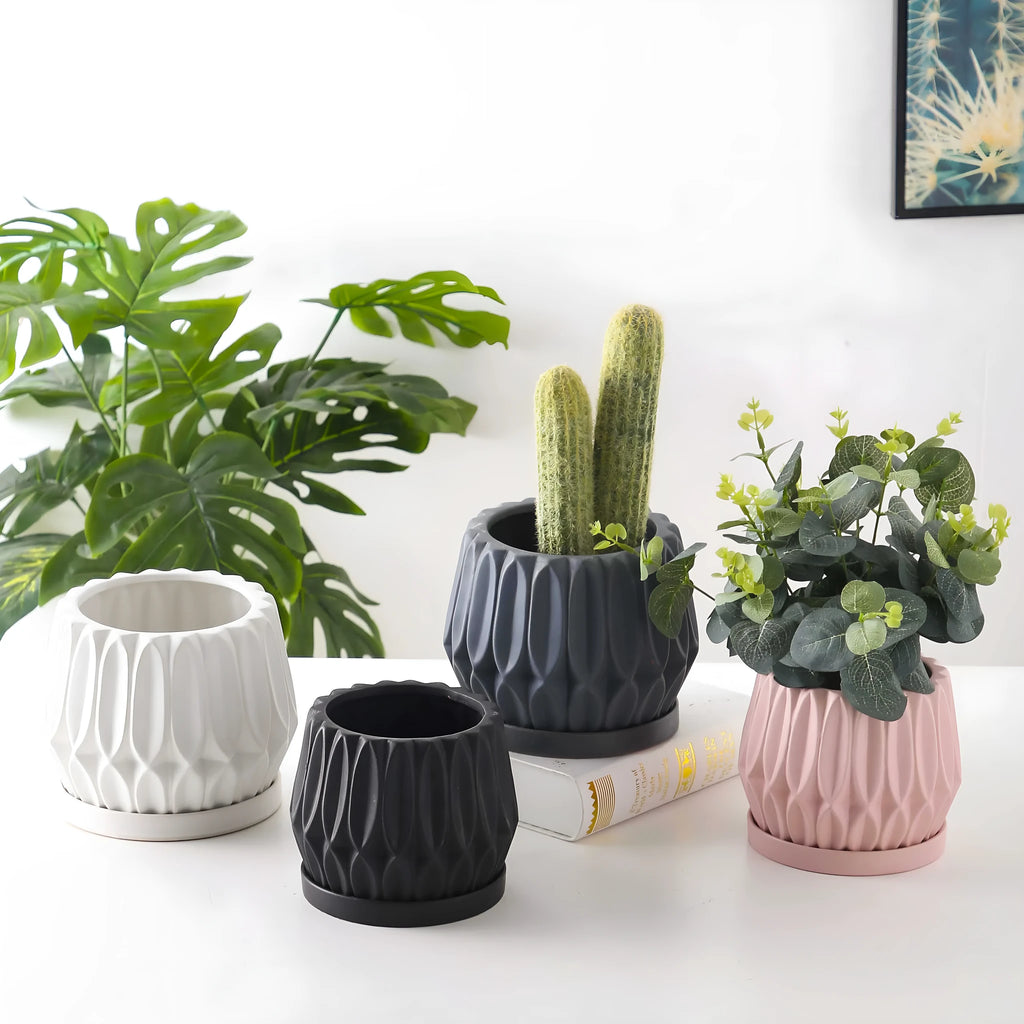 Grey small ceramic tabletop plant flowerpot on a desktop with a small green plant