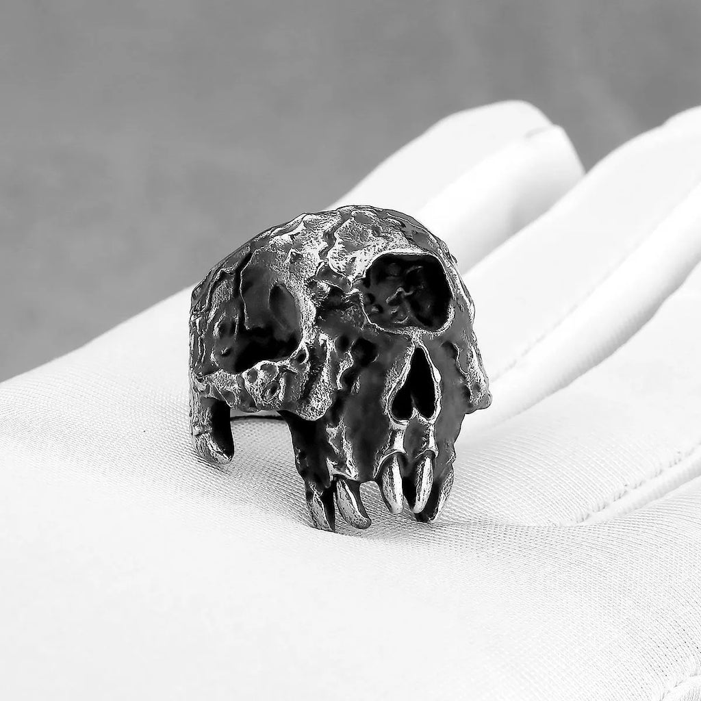 A close-up of a silver-toned alloy ring featuring a detailed one-eyed skull design.