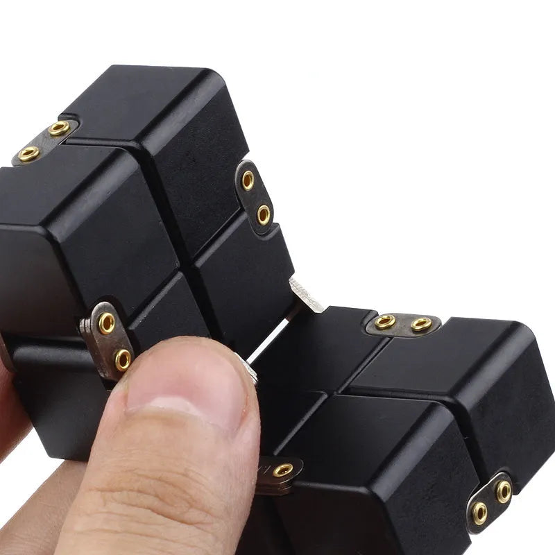 Zinc alloy infinity cube fidget toy showing black and silver rotating cube puzzle on a desk.