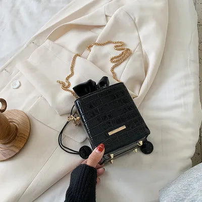 Small green women's bucket bag with a metal chain strap, shown worn cross-body, with zip open revealing interior ID pocket.