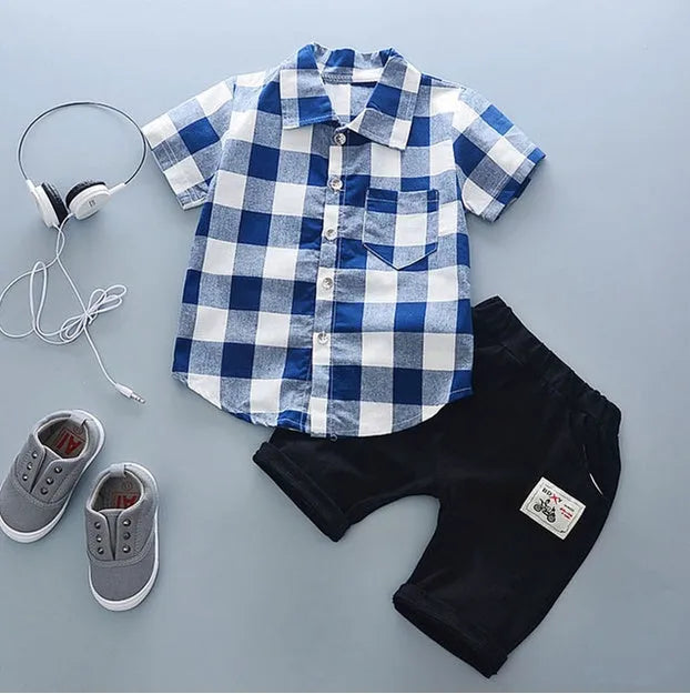 Baby boy wearing a blue cotton short sleeve t-shirt and matching short pants from a summer sports outfit set.