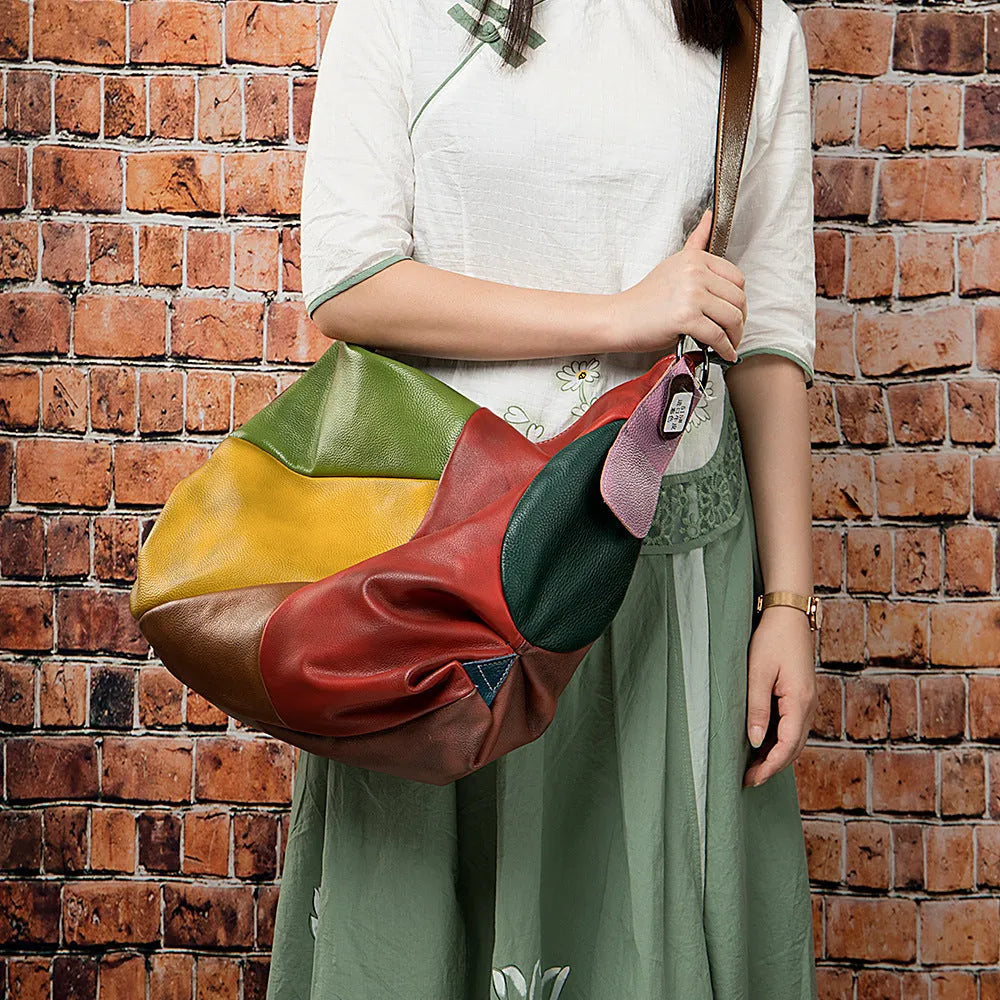 Brown cowhide leather crossbody travel bag showing main compartment open next to a 15-inch laptop and A4 magazine.