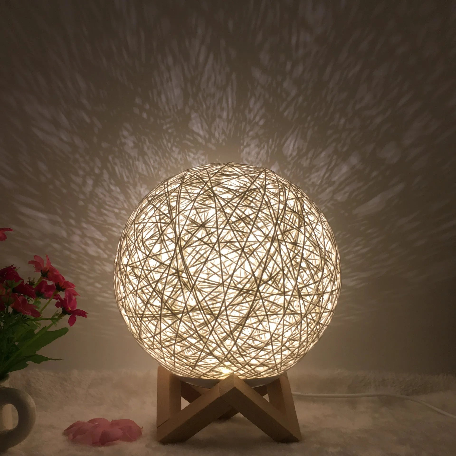 Rattan ball table lamp with woven shade and warm LED lighting on wooden surface