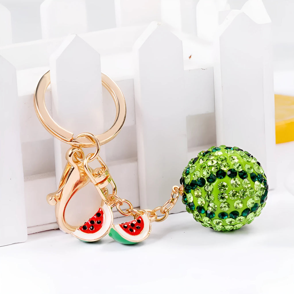 Green watermelon-shaped metal keychain on a white background.
