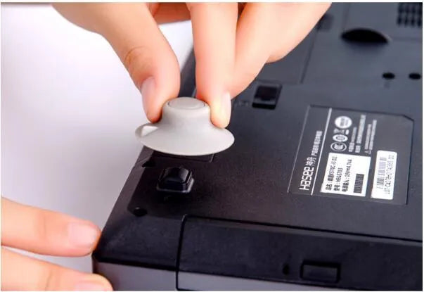 Set of four grey plastic laptop cooling pads with non-slip rubber feet, shown elevating a silver laptop.