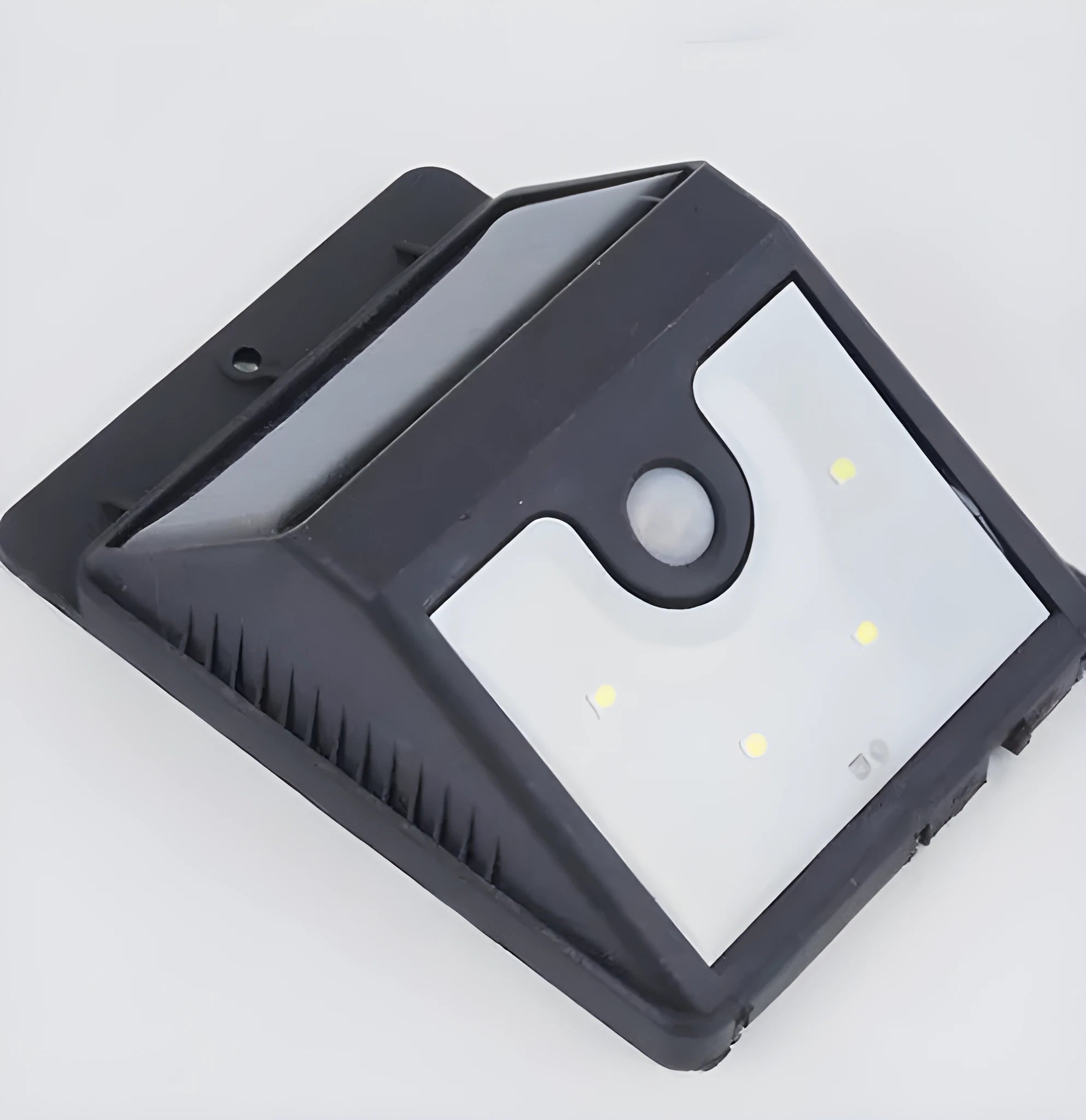 White round solar-powered motion sensor light on an adjustable metal stake in a garden setting.