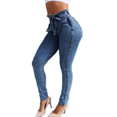 Pair of light blue fringed jeans with distressed hem detailing on a denim background.