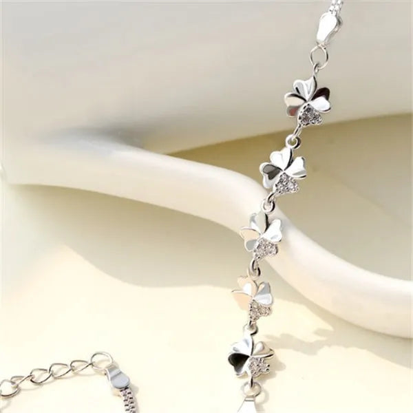 Silver four-leaf clover bracelet with adjustable chain on white background