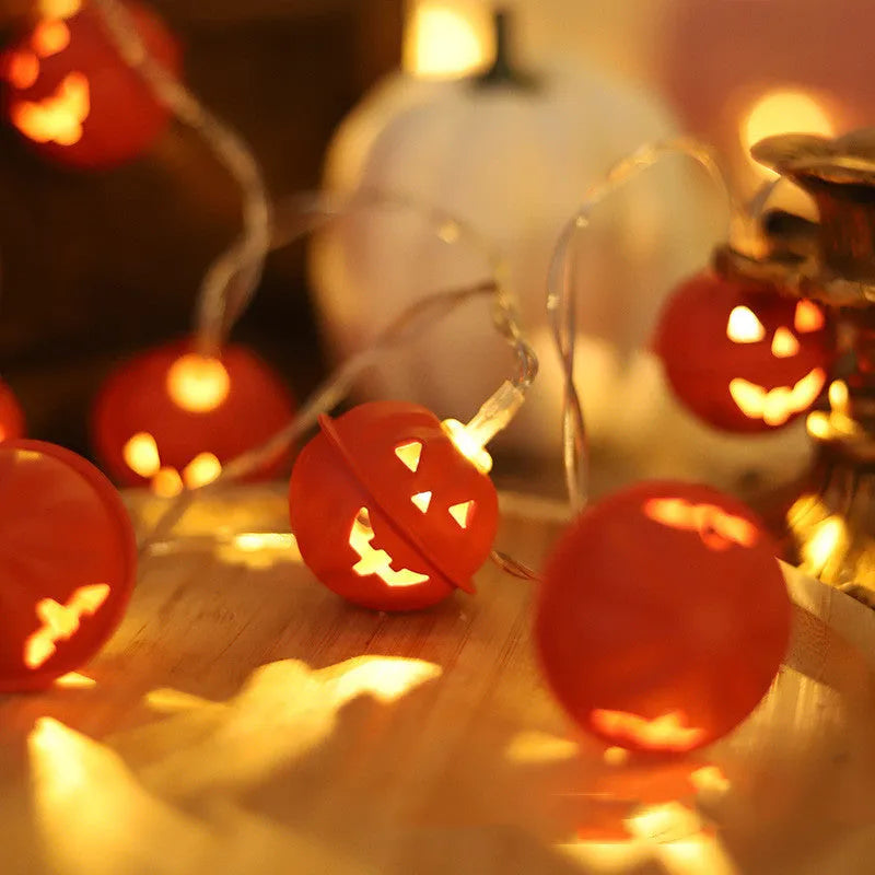 LED Halloween string lights with warm white glow and iron pumpkin pendants on a dark background