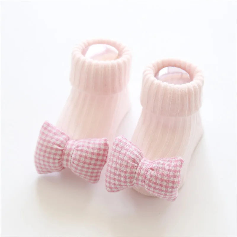 Cotton baby floor socks in various colours and patterns including pink bows, grey stars, and panda design.