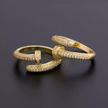 Close-up of a gold plated geometric nail ring with inlaid drill details on a metallic surface.