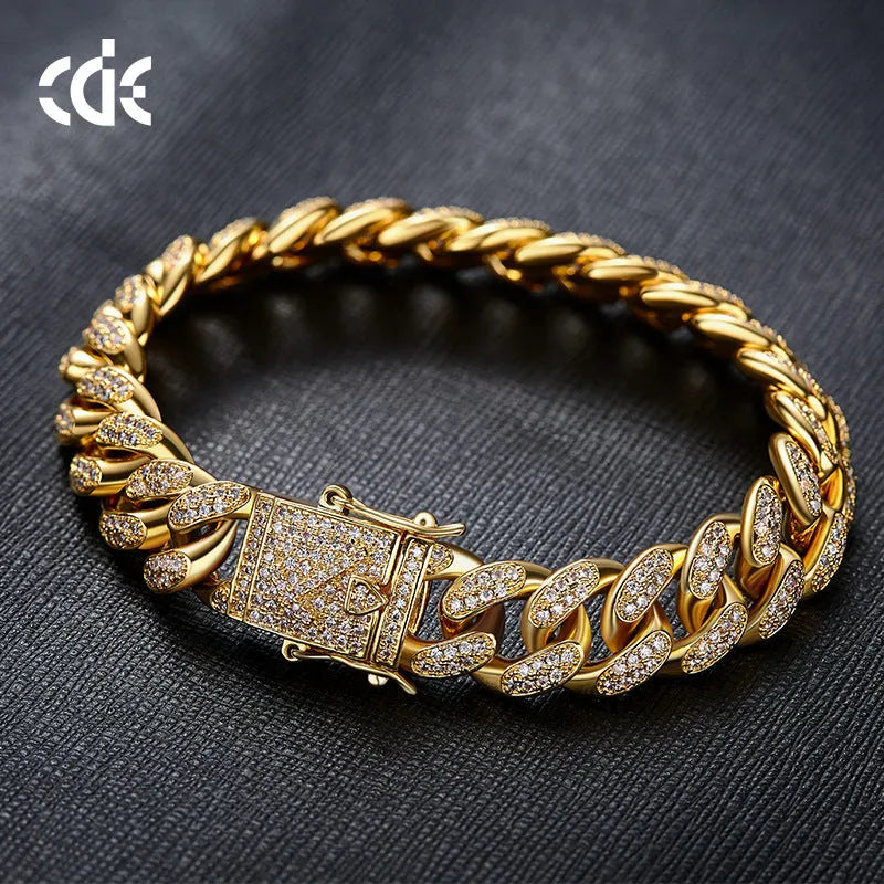 Men's gold Cuban chain bracelet with geometric alloy pendant set with a zircon stone on a neutral background