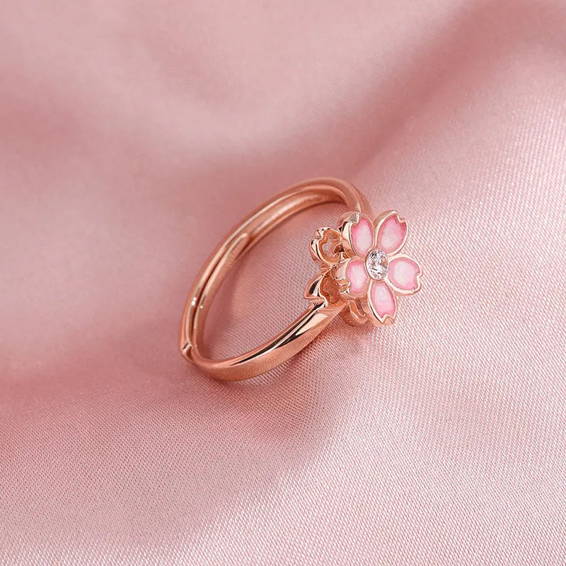 Cherry blossom rotatable ring with rose gold finish, adjustable opening, and silver base shown on a finger