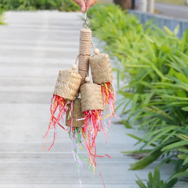 A parrot toy made of wood and sisal rope with colourful shredded paper attachments.