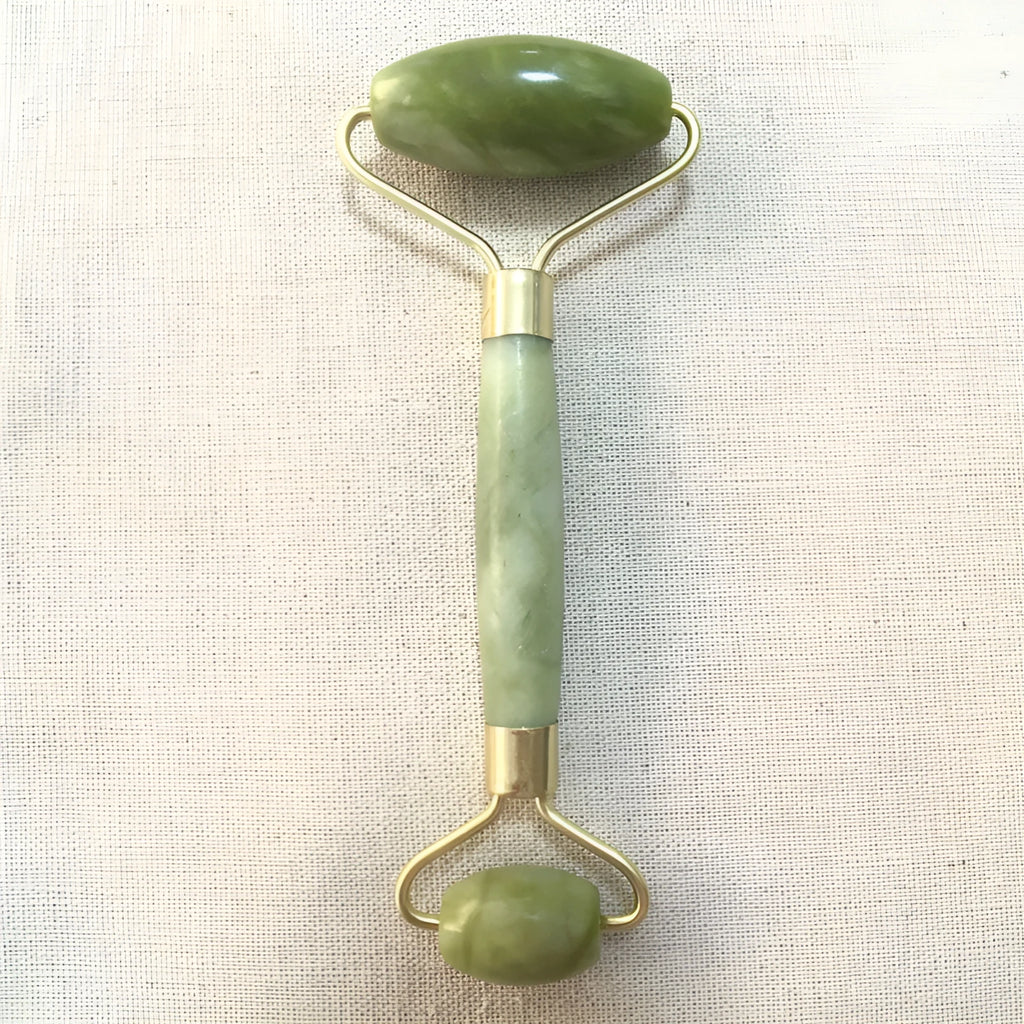 Natural Xiuyu jade double-end roller with green stone, hand-polished finish, large and small wheels on a flat surface