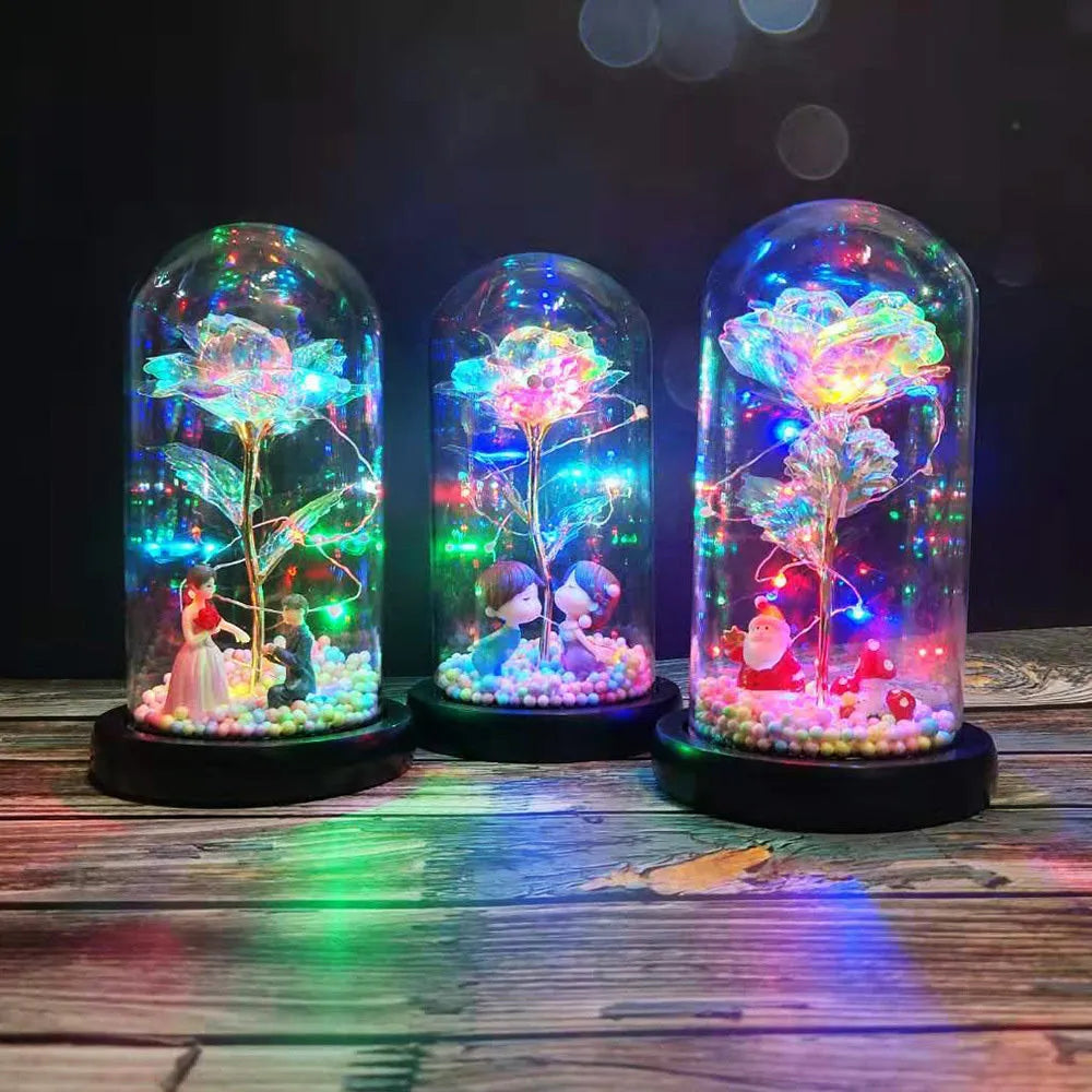 Artificial gold rose in clear glass dome on black base with LED lights for home decor