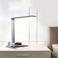 Black and white multi-function LED desk lamp with integrated wireless charging pad for mobile phones.