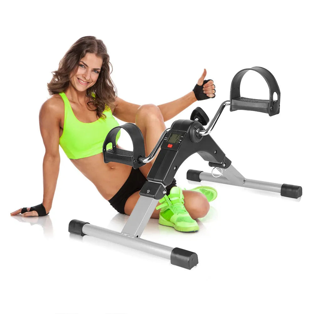 Silver and black exercise mini spinning bike on hard floor with pedals and non-slip foot pads