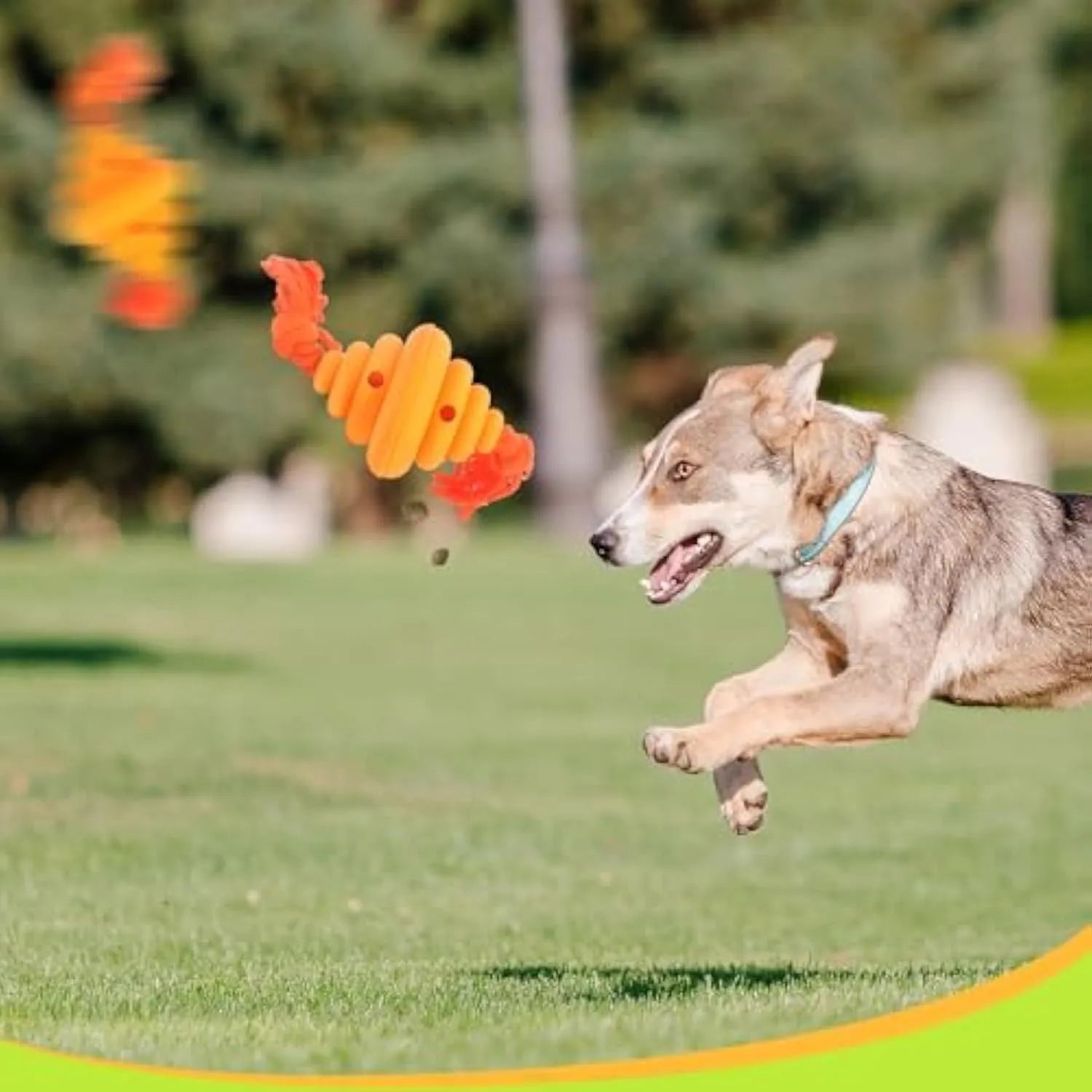 Green and yellow silicone dog ball with knotted rope attached, showing food dispenser openings.