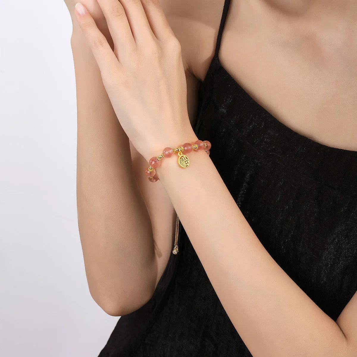 Women's strawberry quartz bracelet with geometric charms and fu character on wrist