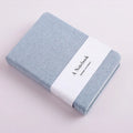 Wire bound notebook with cloth cover showing horizontal line and blank pages, available in blue, dark, dark grey, and pink