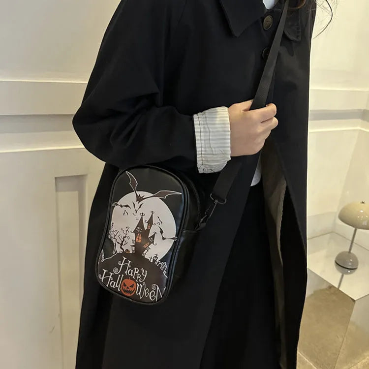 Black Halloween crossbody bag with orange pumpkin, white ghost, and bat graffiti print, shown on a model.