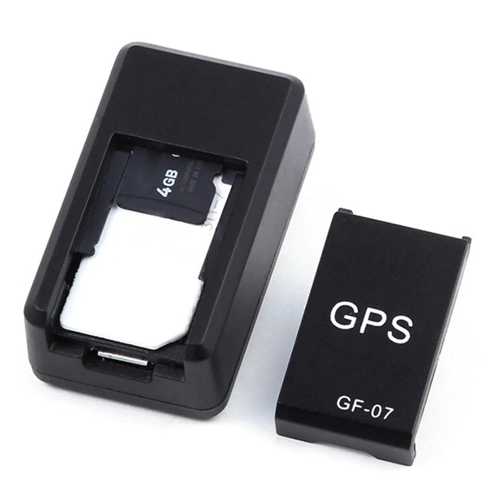 Small black magnetic GPS tracker device next to a micro-USB cable on a table.