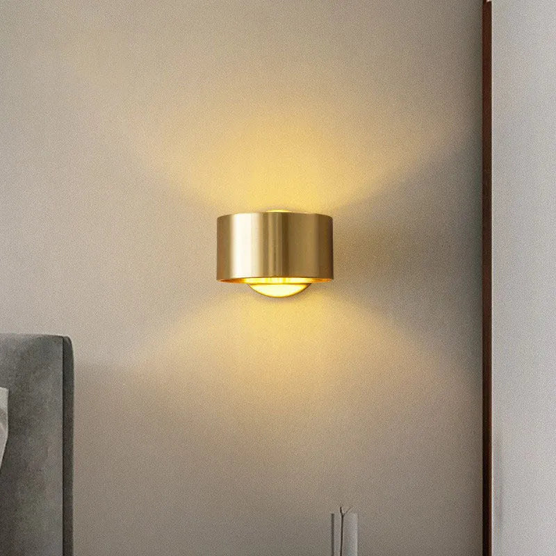 A modern simplistic copper wall lamp shown in a living room setting.