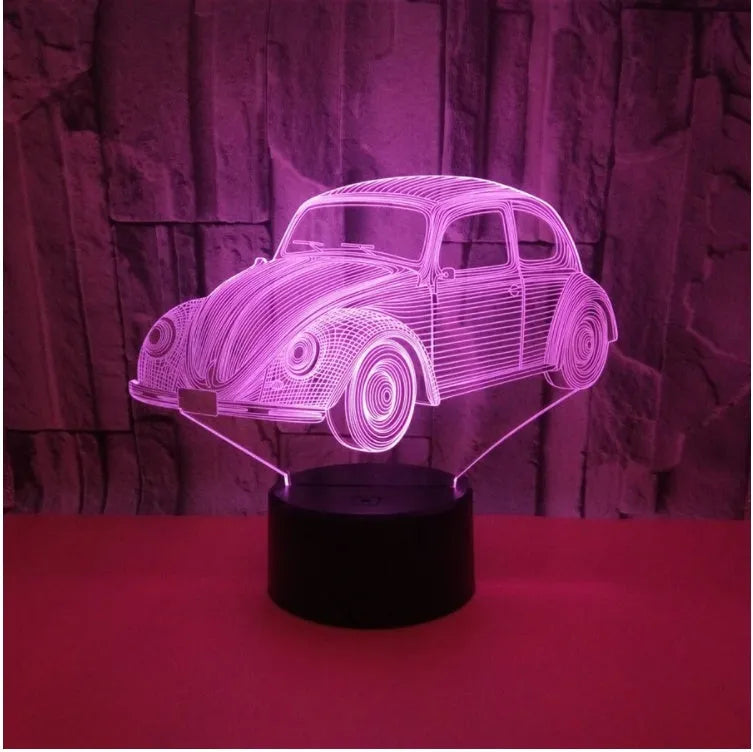 Small black 3D LED table lamp with colourful light effects and a remote control on a desk.