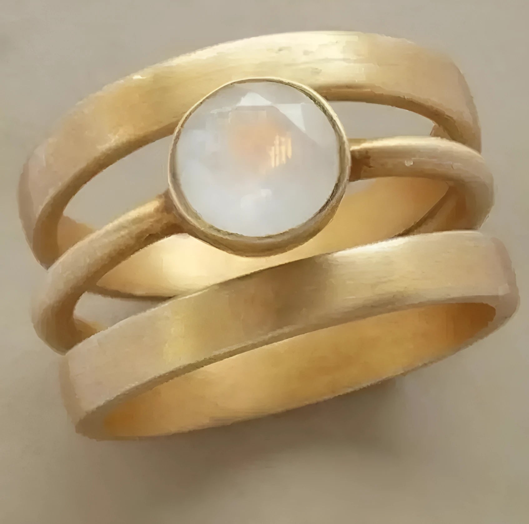Gold-plated geometric titanium steel ring with a micro-inlaid white chalcedony stone on a grey background.