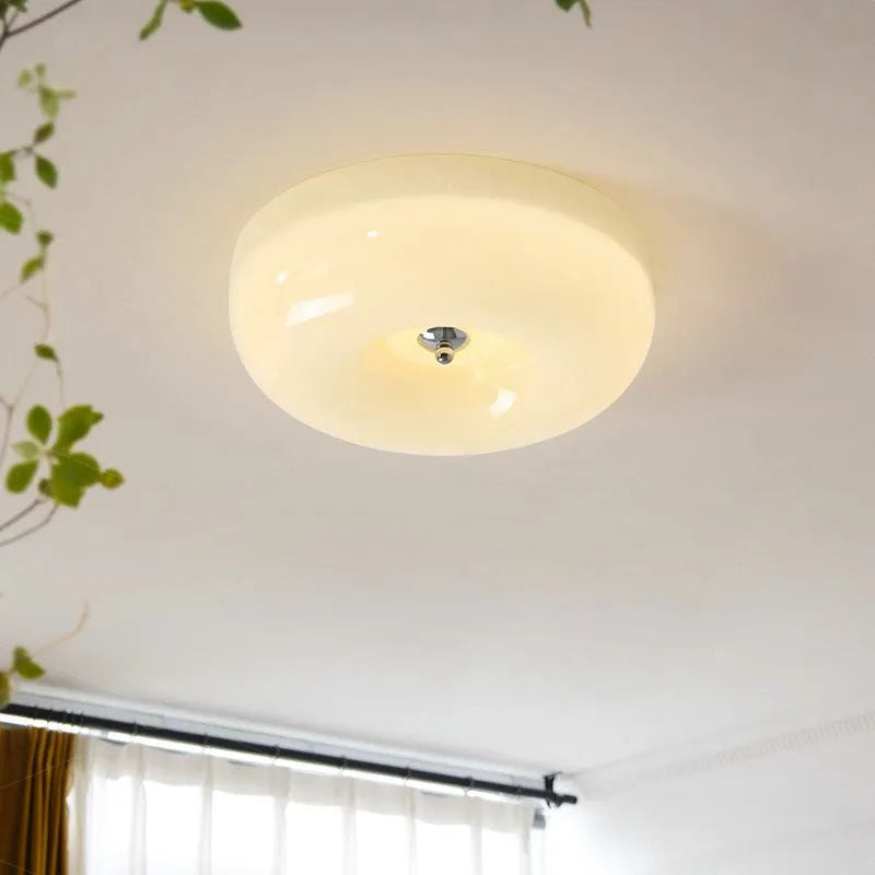 Creamy yellow and white opal shade ceiling light with remote control on a bedroom ceiling.