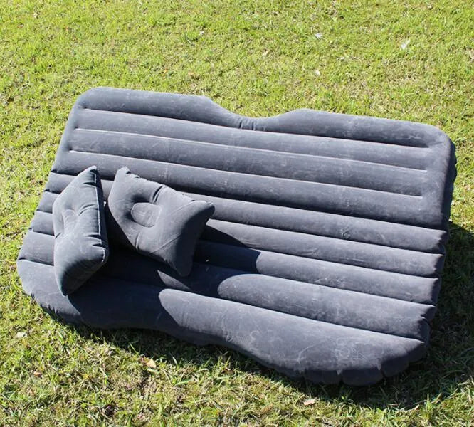 Inflatable car bed with flocking material shown in vehicle with two pillows and storage bag