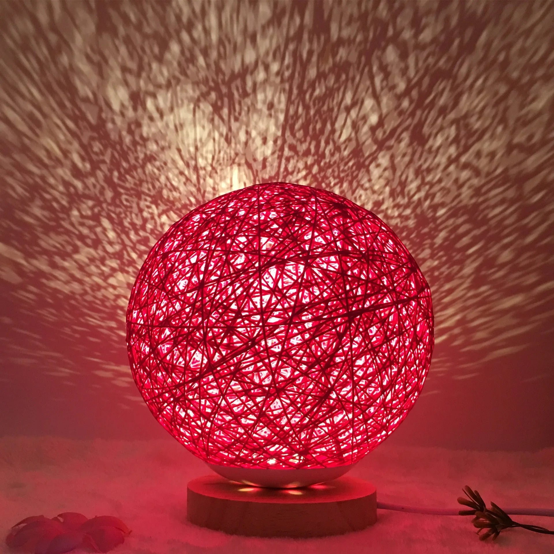 Rattan ball table lamp with woven shade and warm LED lighting on wooden surface