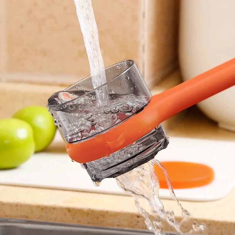 Light green kitchen peeler with a small orange storage bucket attached underneath the blade.