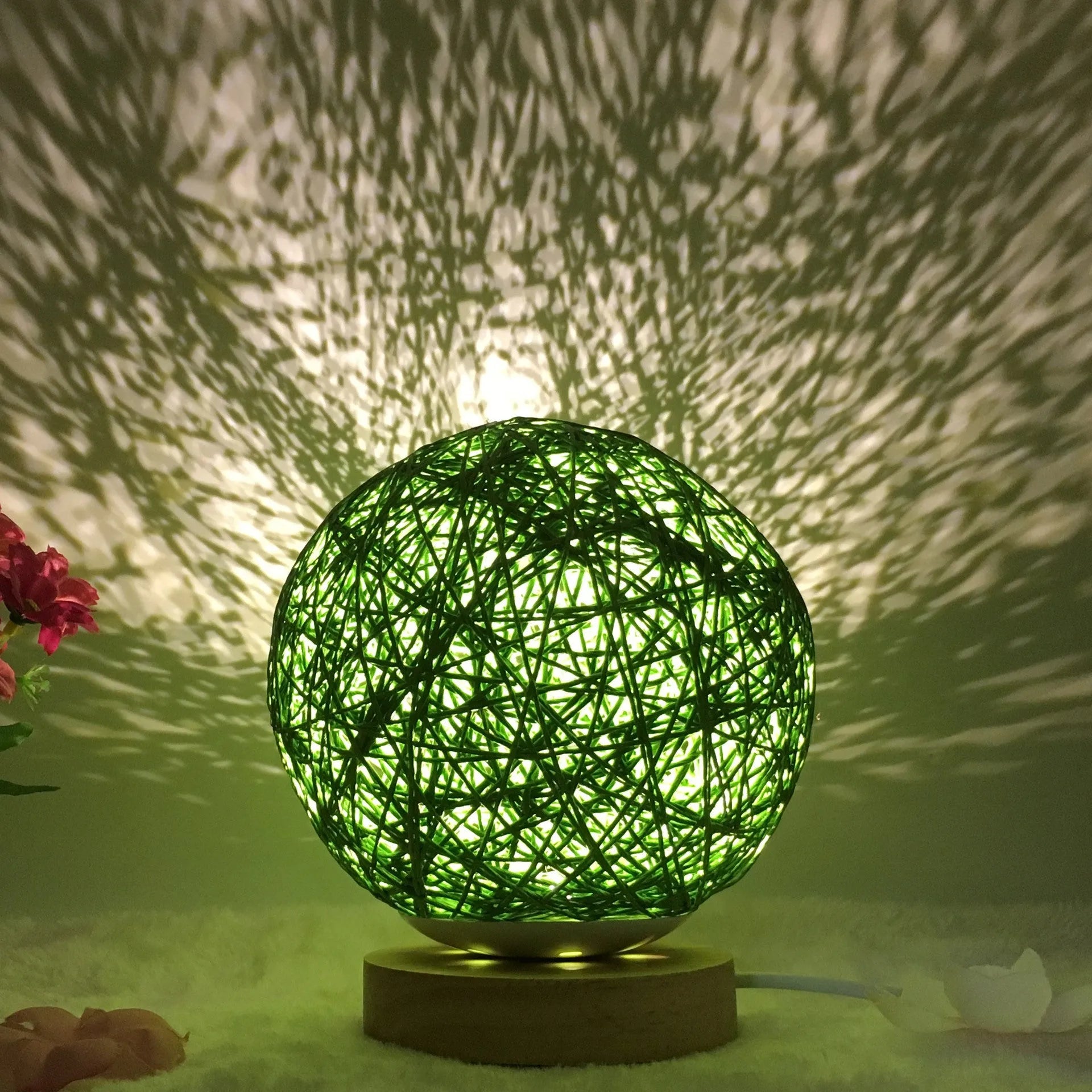 Rattan ball table lamp with woven shade and warm LED lighting on wooden surface