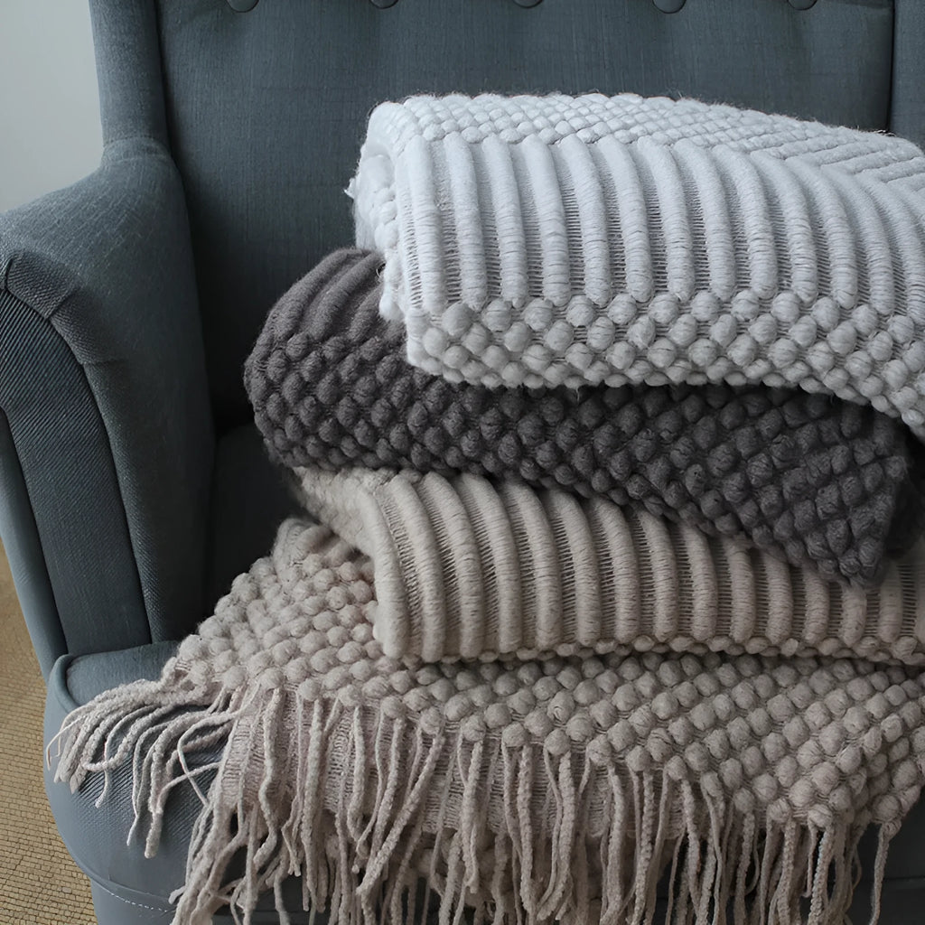 Small grey polyester nap blanket measuring 127 by 170 centimetres folded on a sofa.