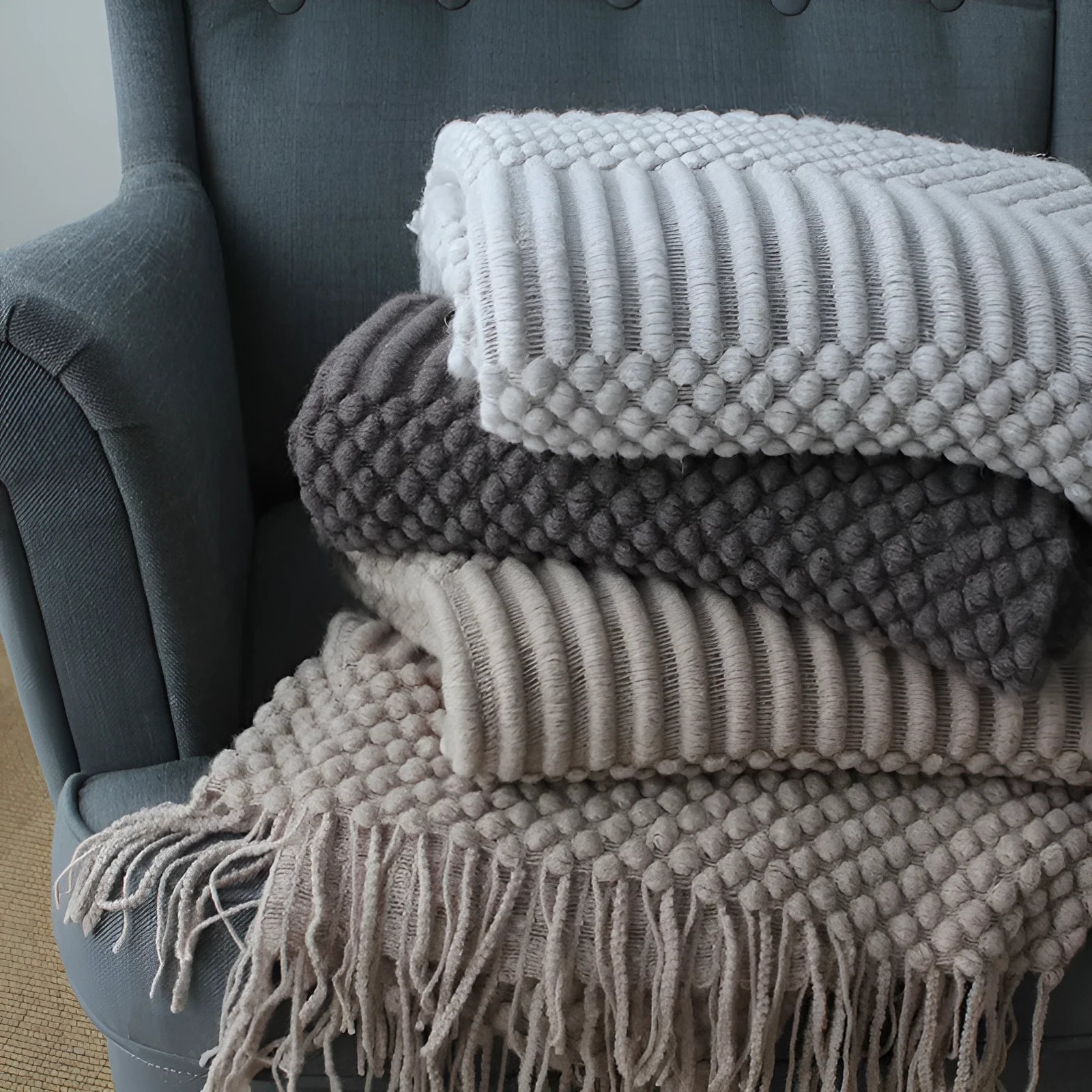 Small grey polyester nap blanket measuring 127 by 170 centimetres folded on a sofa.