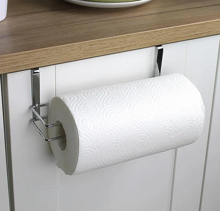 Silver stainless steel rack hanging on the back of a kitchen cabinet door holding a paper towel roll.
