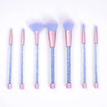 Set of 7 makeup brushes with pink handles, black bristles, and long plastic handles on a light background