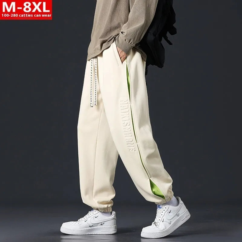 Man wearing loose-fit black trousers with printed stitching detail and a banded ankle cuff.