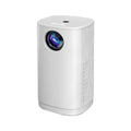 Blue mini projector with remote control on table showing movie projection on wall
