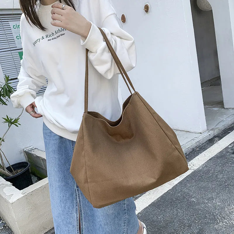 Women's solid colour canvas handbag showing horizontal square shape and double shoulder straps