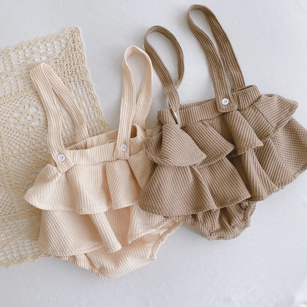 Baby girl wearing a pleated lotus leaf design cotton romper in a triangle climb style.