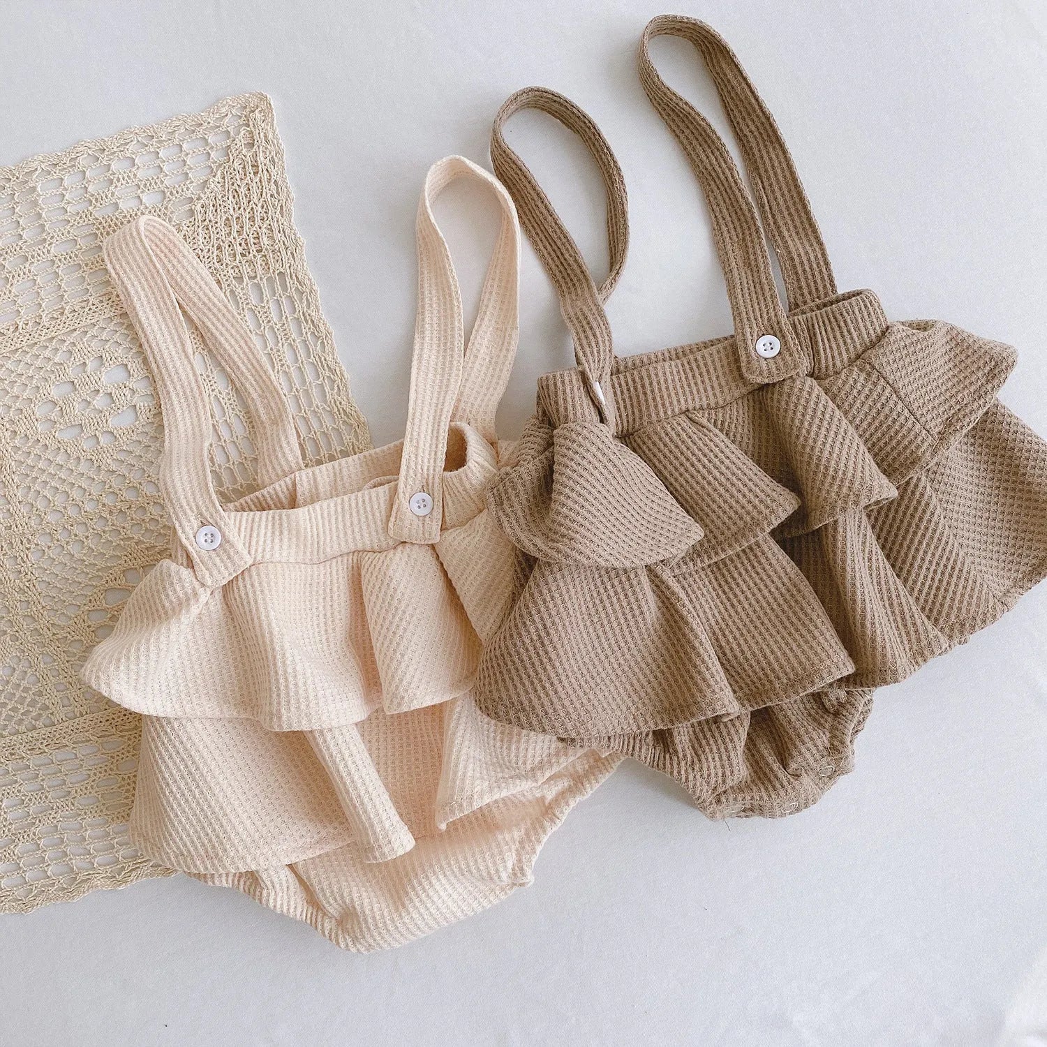 Baby girl wearing a pleated lotus leaf design cotton romper in a triangle climb style.
