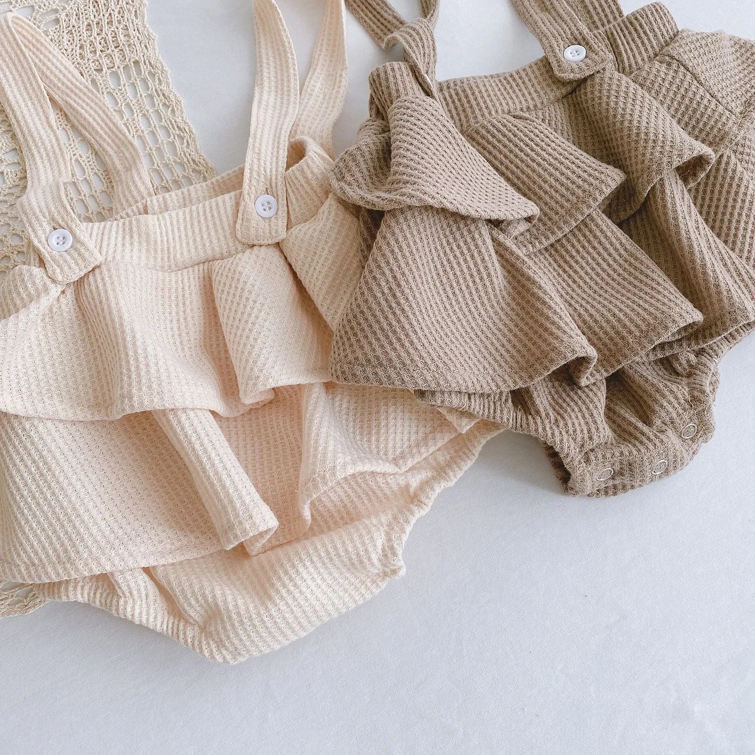 Baby girl wearing a pleated lotus leaf design cotton romper in a triangle climb style.