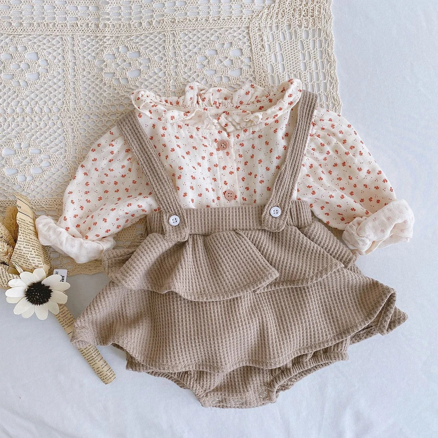 Baby girl wearing a pleated lotus leaf design cotton romper in a triangle climb style.