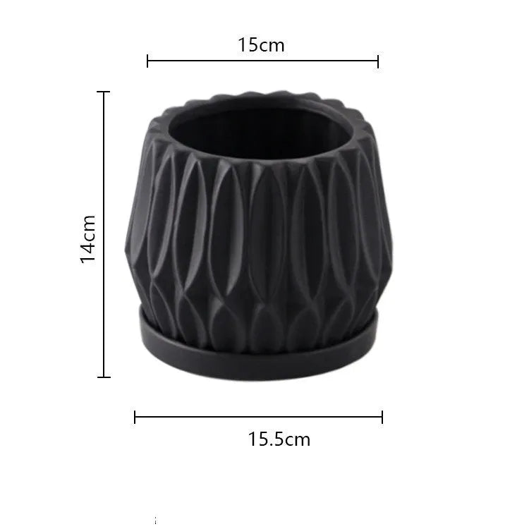Grey small ceramic tabletop plant flowerpot on a desktop with a small green plant