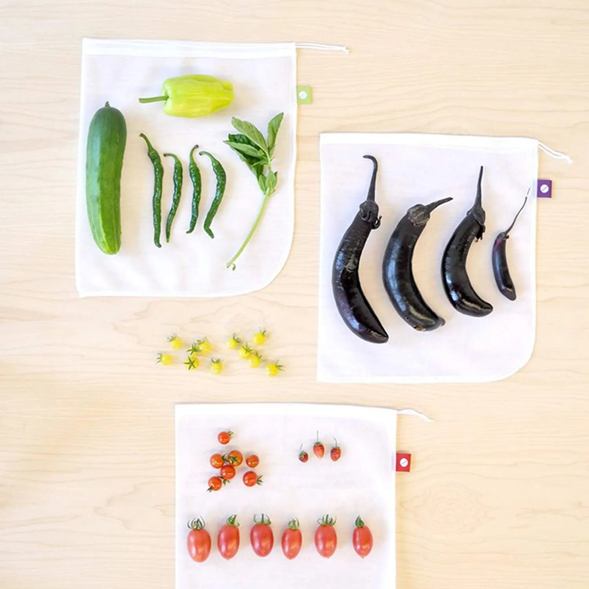 Five white cotton drawstring bags for kitchen vegetable storage arranged on a clean surface