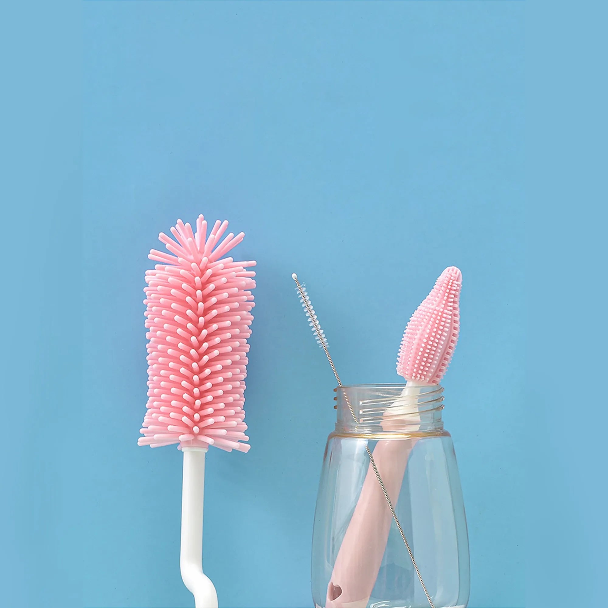 Three silicone baby bottle brushes in pink, blue, and yellow colours including a straw cleaning brush.